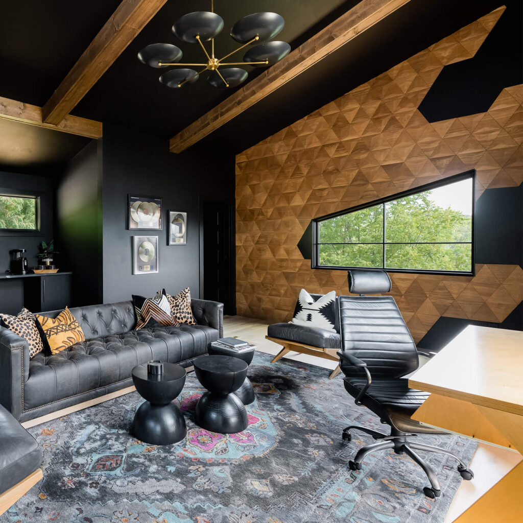 A luxury home office featuring a modern desk setup with an ergonomic leather chair, positioned in front of a geometric accent wall made of oak Pyramid 3D wooden panels.