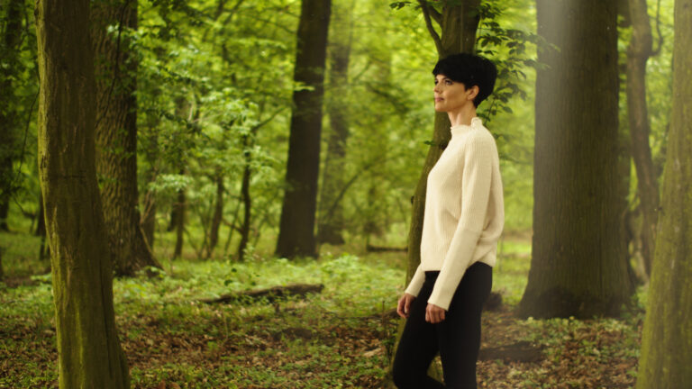 Osoba spacerująca po lesie, symbolizująca naturalne projektowanie wnętrz