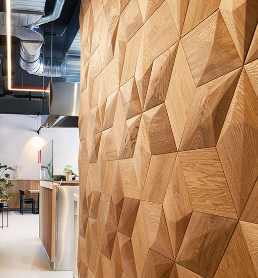Moderne 3D-Wandpaneele aus Eiche in Rautenform in einem Interieur im Industrial-Stil mit sichtbaren Rohrleitungen an der Decke.