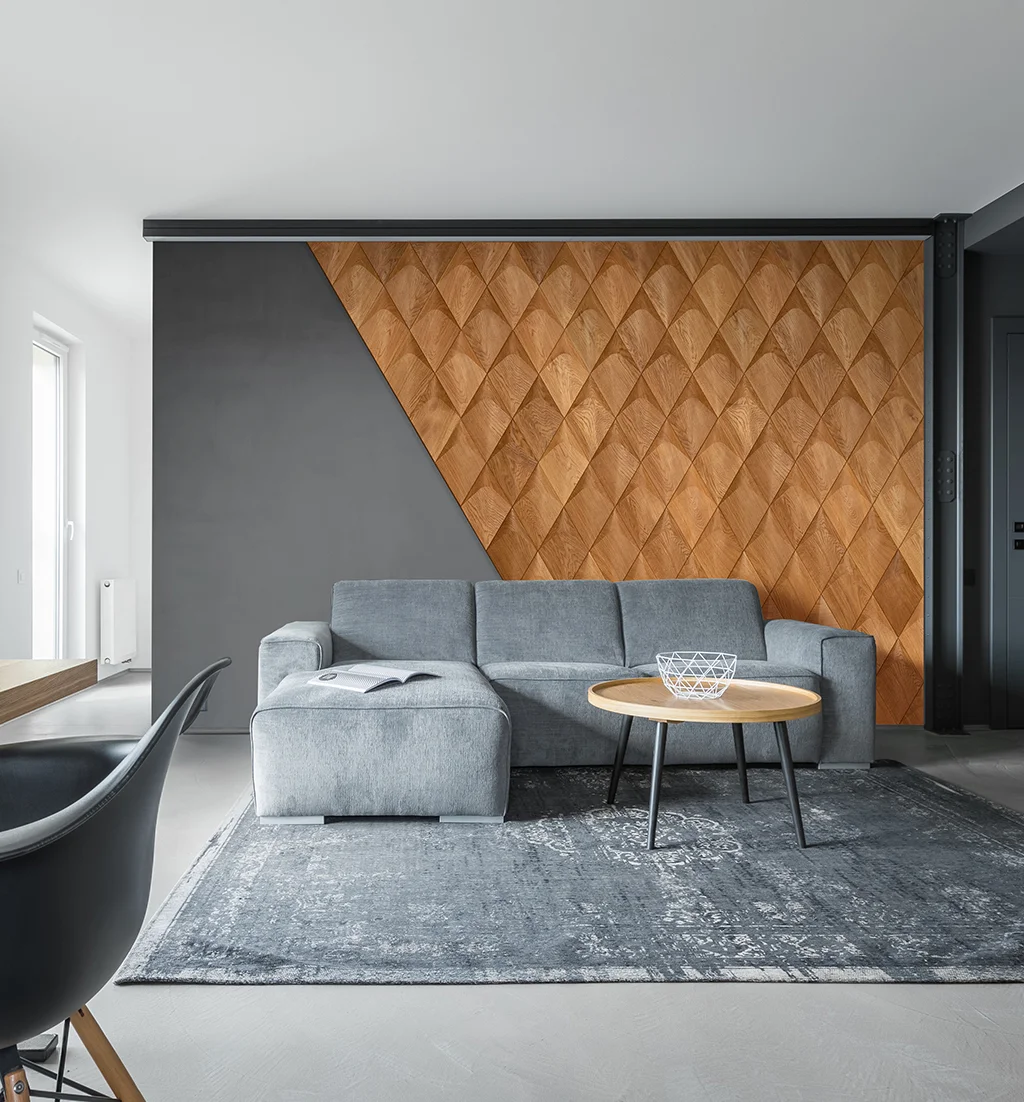 Modernes Wohnzimmer mit grauer Couch und geometrischen 3D-Wandpaneelen aus Eiche in Rautenform.