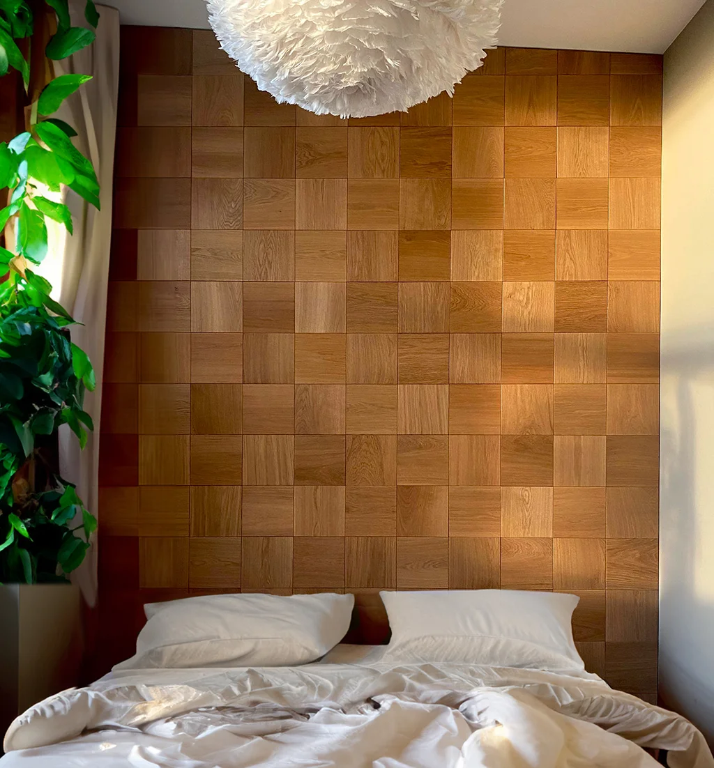 Gemütliches Schlafzimmer mit einer dekorativen Akzentwand aus quadratischen Eichenholzpaneelen hinter dem Bett.