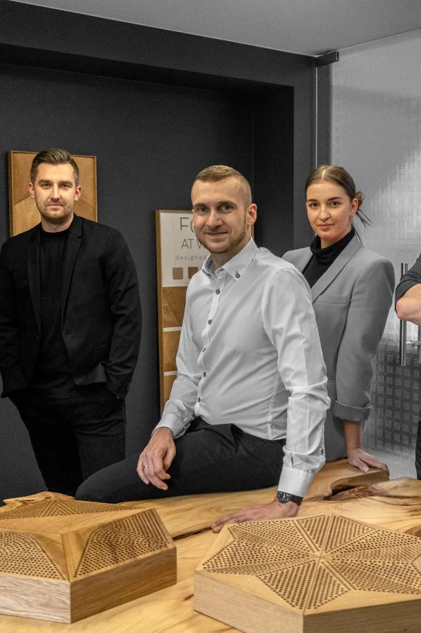 Design team presenting 3D oak acoustic Hexagon panels on a wooden table in a modern office environment.